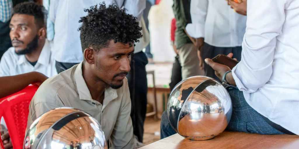 Participants engaging with Worldcoin registration orb at an event.